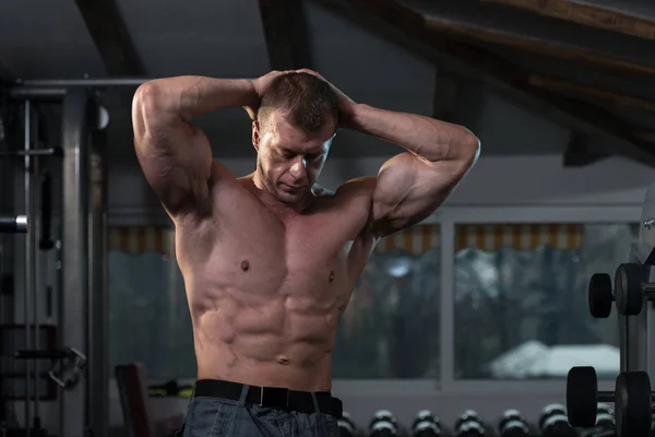 Musculoso hombre flexionando los músculos en el gimnasio — Foto de Stock