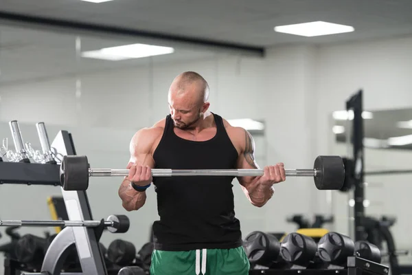 Mannen i gymmet träna biceps med skivstång — Stockfoto