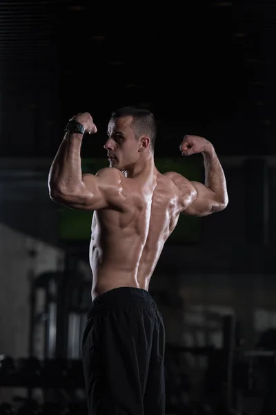 Homem muscular que flexiona a dose dos músculos traseiros — Fotografia de Stock