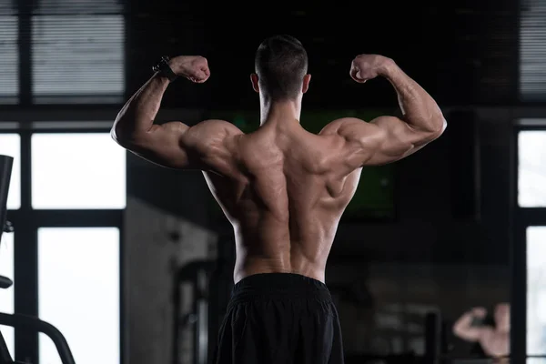 Homem muscular que flexiona a dose dos músculos traseiros — Fotografia de Stock