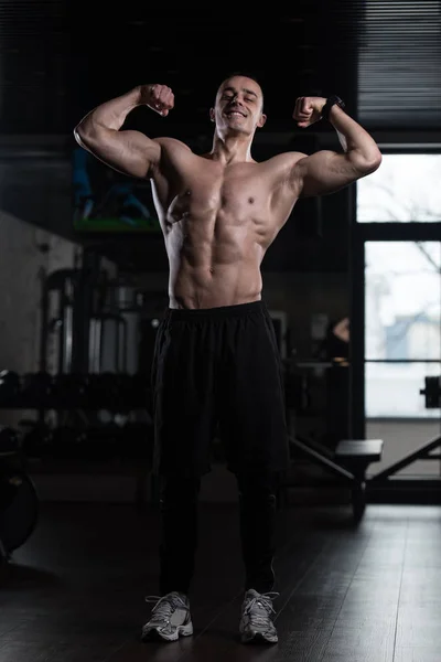 Homem muscular flexionando músculos no ginásio — Fotografia de Stock