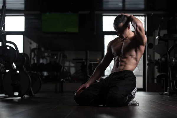 Homem muscular flexionando músculos no ginásio — Fotografia de Stock