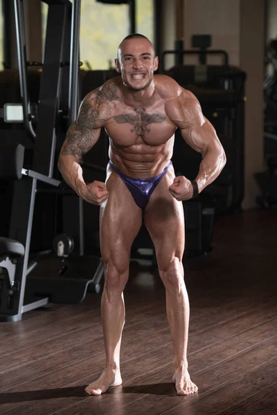 Muscular Man Flexing Muscles In Gym