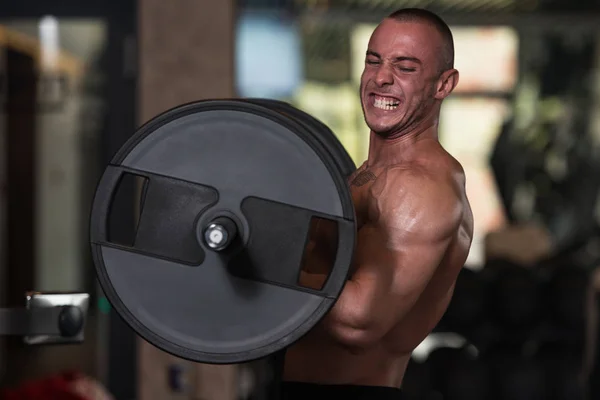 Culturista ejercitando bíceps con barra en el gimnasio —  Fotos de Stock