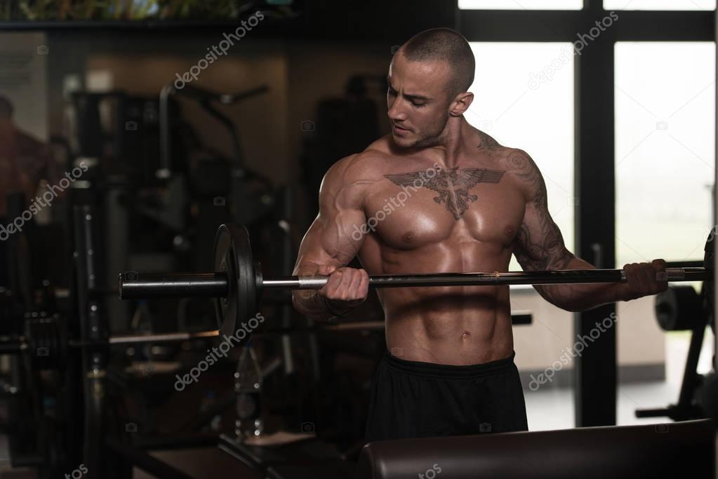 Man In The Gym Exercising Biceps With Barbell