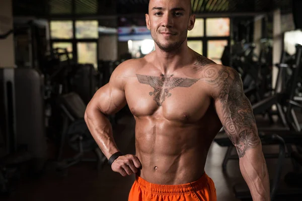 Homem muscular flexionando músculos no ginásio — Fotografia de Stock