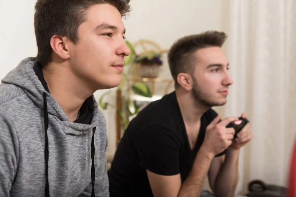 Två stiliga unga män spelar TV-spel i rum — Stockfoto