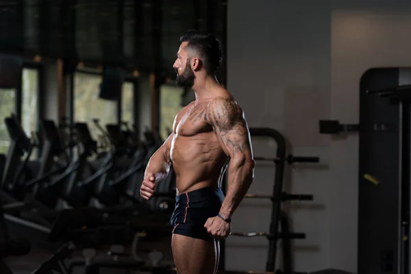 Мускулистый мужчина сгибает мышцы в спортзале — стоковое фото