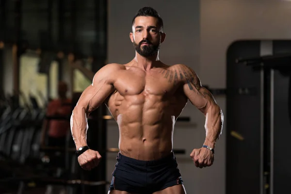 Homem muscular flexionando músculos no ginásio — Fotografia de Stock