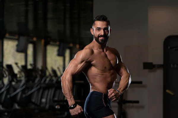 Hombre musculoso guapo flexionando músculos en el gimnasio —  Fotos de Stock