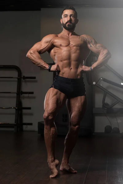 Homem muscular flexionando músculos no ginásio — Fotografia de Stock