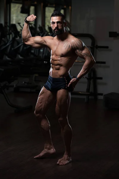 Musclé homme flexion des muscles dans la salle de gym — Photo