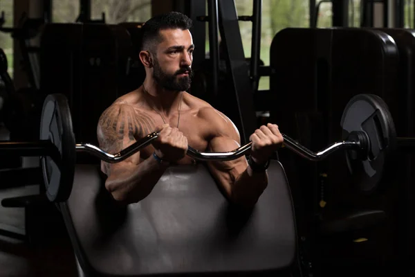 Hombre muscular ejercitando bíceps con barra — Foto de Stock