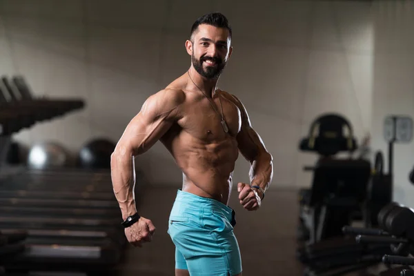 Musculoso hombre flexionando los músculos en el gimnasio —  Fotos de Stock