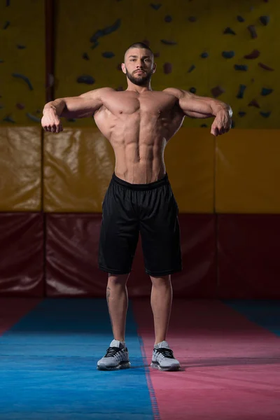 Knappe gespierde Man buigen spieren In sportschool — Stockfoto