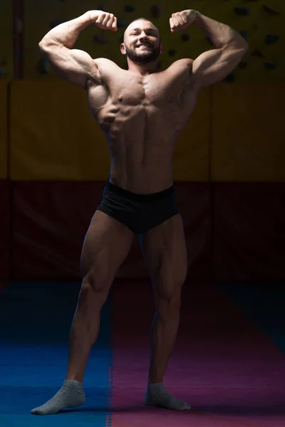 Homem muscular flexionando músculos no ginásio — Fotografia de Stock