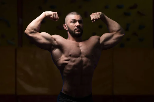 Gespierd lichaam bouwer tonen zijn voorzijde dubbele biceps — Stockfoto