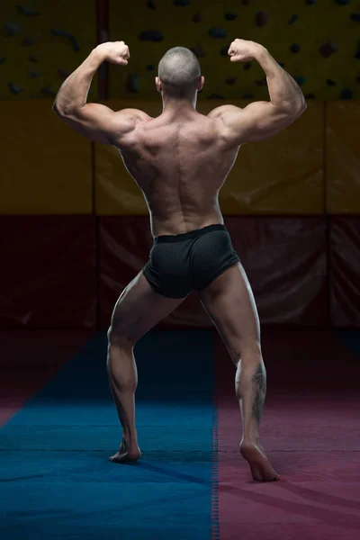 Bodybuilder musculaire montrant son dos double biceps — Photo