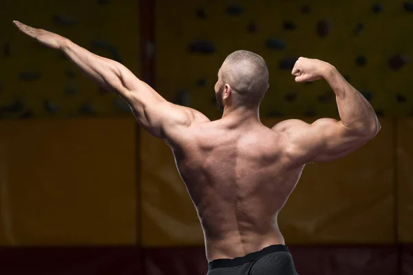 Musculoso hombre flexionando los músculos en el gimnasio — Foto de Stock