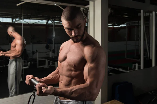 Homem fazendo exercício para bíceps na máquina de cabo — Fotografia de Stock