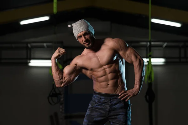 Hombre musculoso guapo flexionando músculos en el gimnasio —  Fotos de Stock