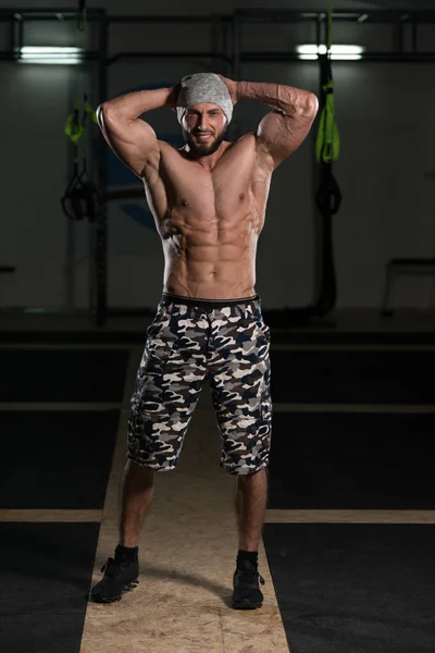 Hombre musculoso guapo flexionando músculos en el gimnasio —  Fotos de Stock