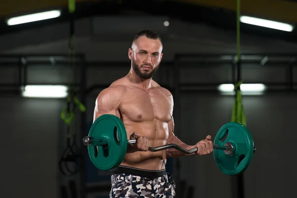 Homem muscular exercitando bíceps com barra — Fotografia de Stock