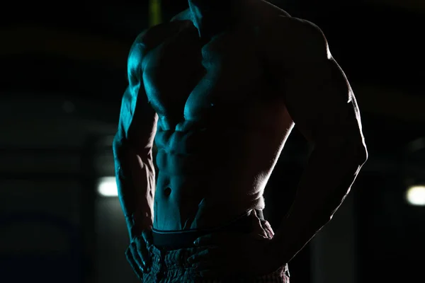 Силуэт мускулистый человек покачивая мышцы в тренажерном зале — стоковое фото