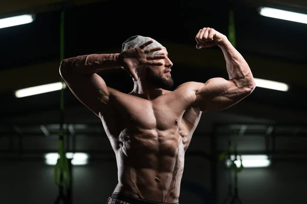 Homem muscular flexionando músculos no ginásio — Fotografia de Stock