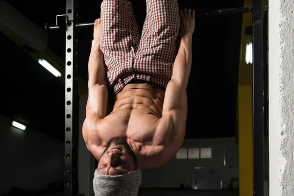 Człowiek wykonuje wiszące nogi podnosi ćwiczenia ABS — Zdjęcie stockowe