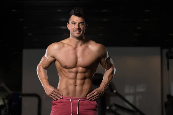 Musculoso hombre flexionando los músculos en el gimnasio —  Fotos de Stock