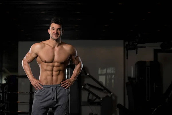 Hombre musculoso guapo flexionando músculos en el gimnasio — Foto de Stock