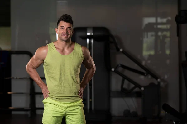 Hombre fuerte en camiseta verde fondo gimnasio —  Fotos de Stock