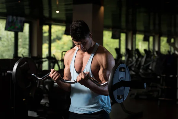 Homem muscular exercitando bíceps com barra — Fotografia de Stock