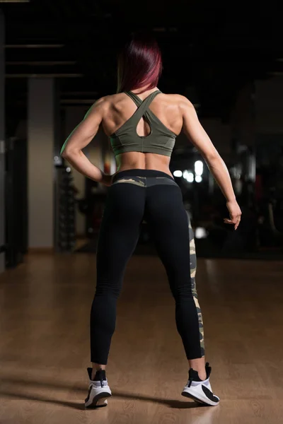 Привлекательная мускулистая женщина, демонстрирующая мышцы в спортзале — стоковое фото