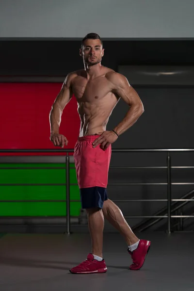 Pohledný svalnatý muž protahuje svaly v tělocvičně — Stock fotografie