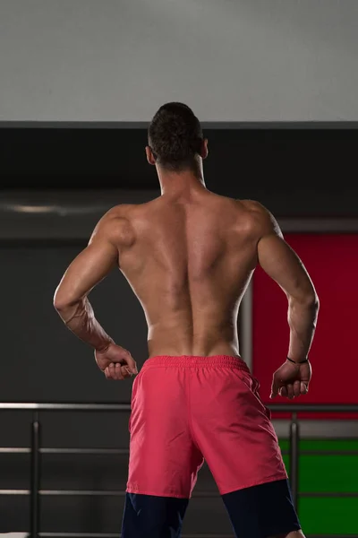 Homem muscular flexionando músculos no ginásio — Fotografia de Stock