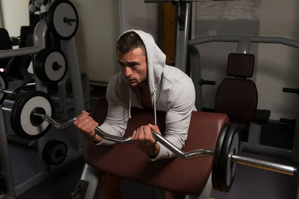 Hombre muscular ejercitando bíceps con barra — Foto de Stock