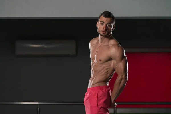 Homem no ginásio mostrando seu corpo bem treinado — Fotografia de Stock