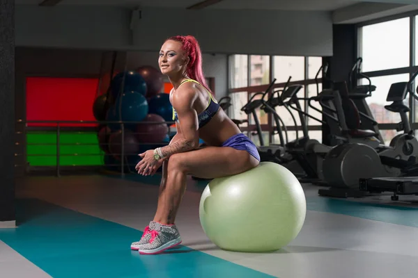 Mujer descansando en la pelota en el gimnasio —  Fotos de Stock