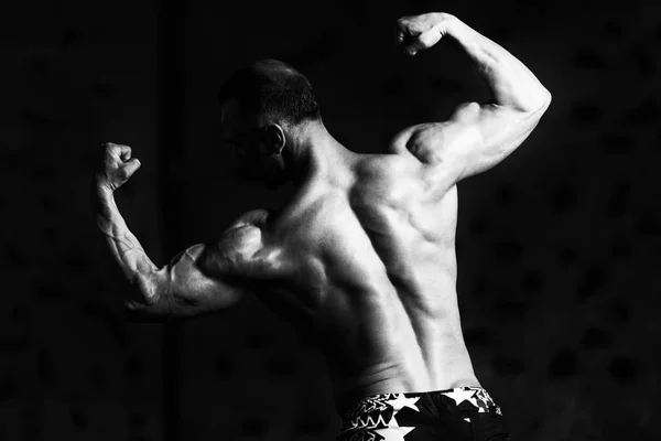 Svalové kulturista, ukazující jeho zpět dvojitý biceps — Stock fotografie