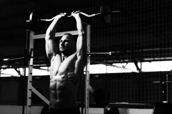 Muscolare uomo che esercita Triceps con bilanciere — Foto Stock