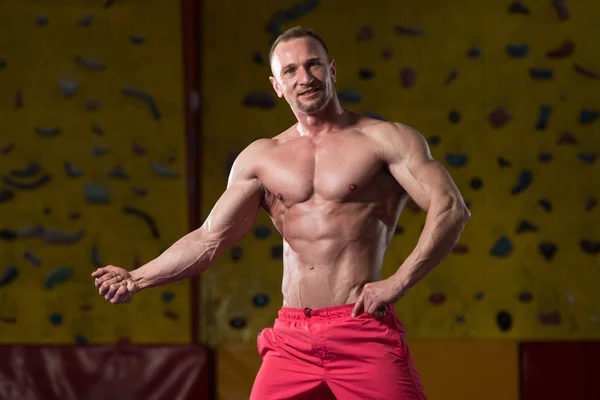 Hombre musculoso guapo flexionando músculos en el gimnasio —  Fotos de Stock