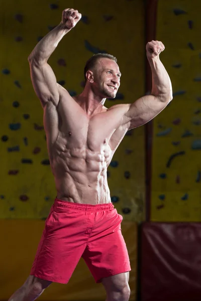 Construtor de corpo muscular mostrando seu bíceps duplo frontal — Fotografia de Stock