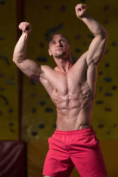 Gespierd lichaam bouwer tonen zijn voorzijde dubbele biceps — Stockfoto