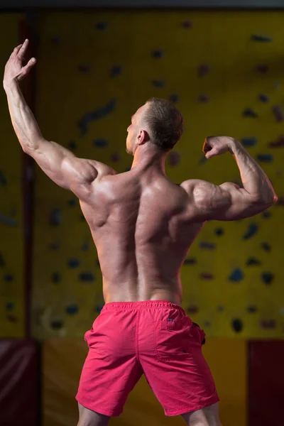 Knappe gespierde Man buigen spieren In sportschool — Stockfoto