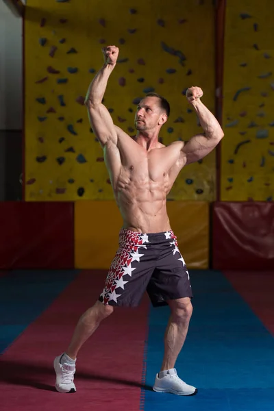 Construtor de corpo muscular mostrando seu bíceps duplo frontal — Fotografia de Stock