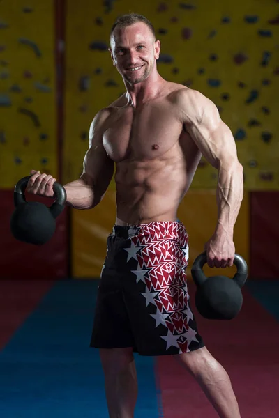 Fitness uomo utilizzando kettlebells dentro palestra — Foto Stock