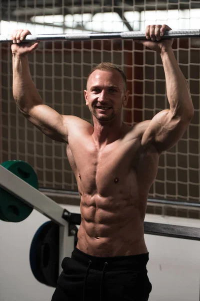 Hombre musculoso guapo flexionando músculos en el gimnasio — Foto de Stock