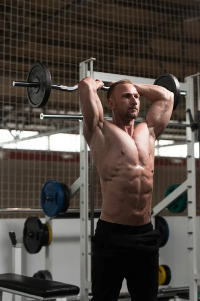 Hombre en el gimnasio haciendo ejercicio tríceps con barra —  Fotos de Stock